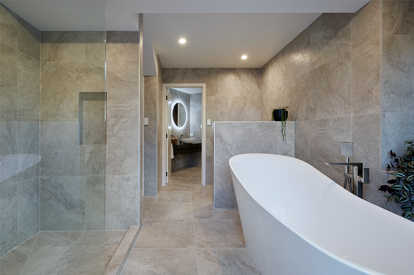 Large beige marble tiled bathroom with a slanted bathtub interior
