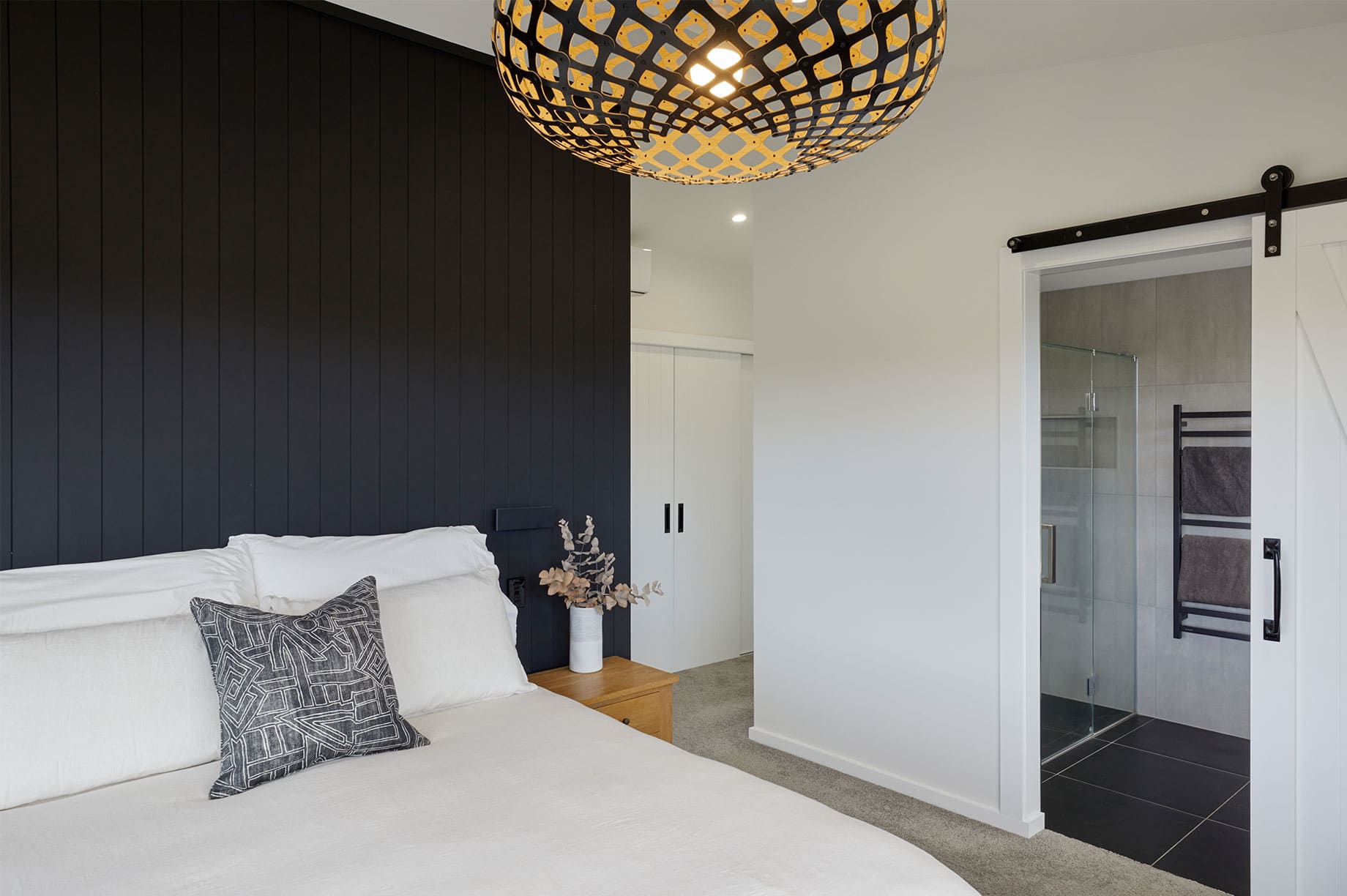 Master bedroom with black wooden panels and an ensuite