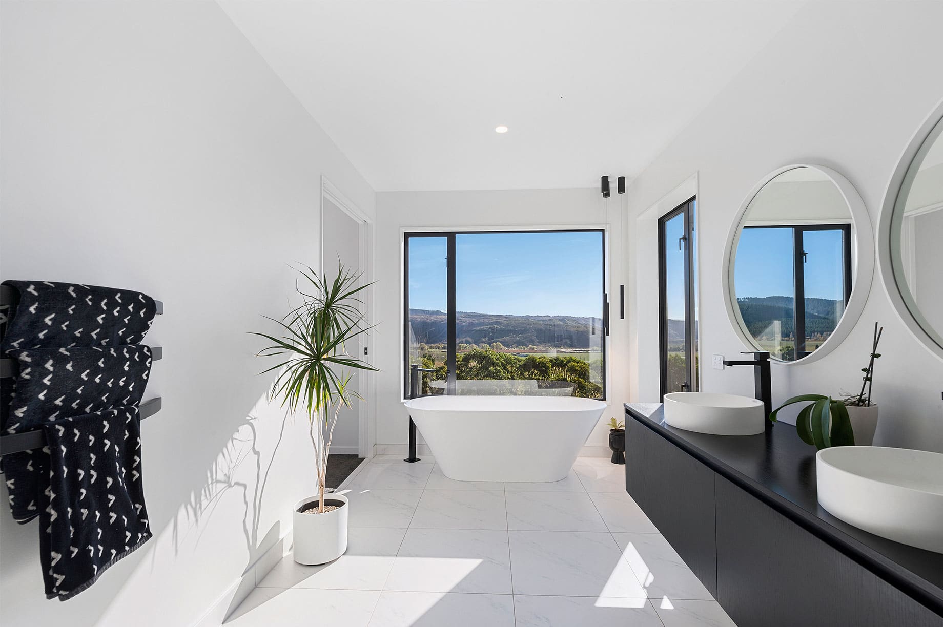 White bathroom with large windows and a hill view
