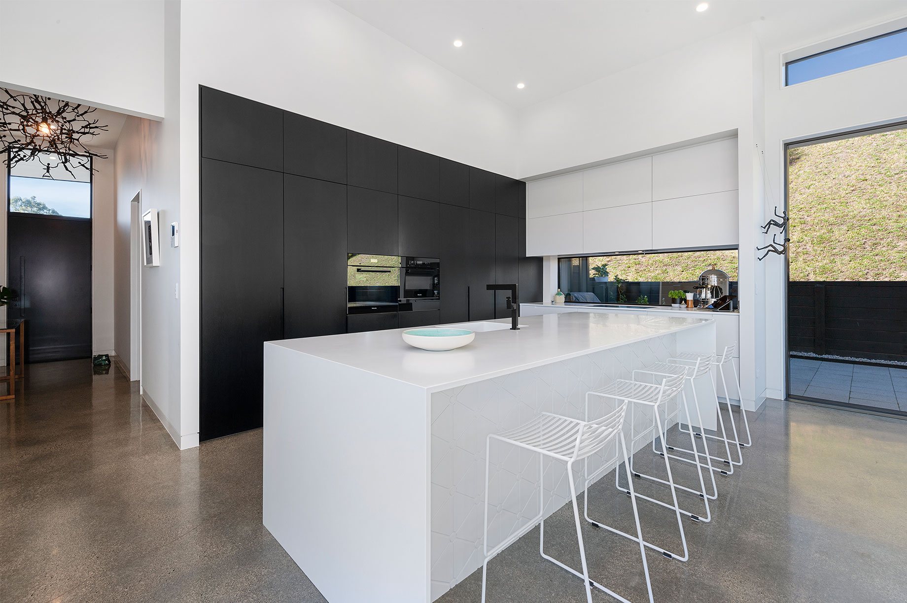 Black kitchen with white kitchen island and barstool chairs