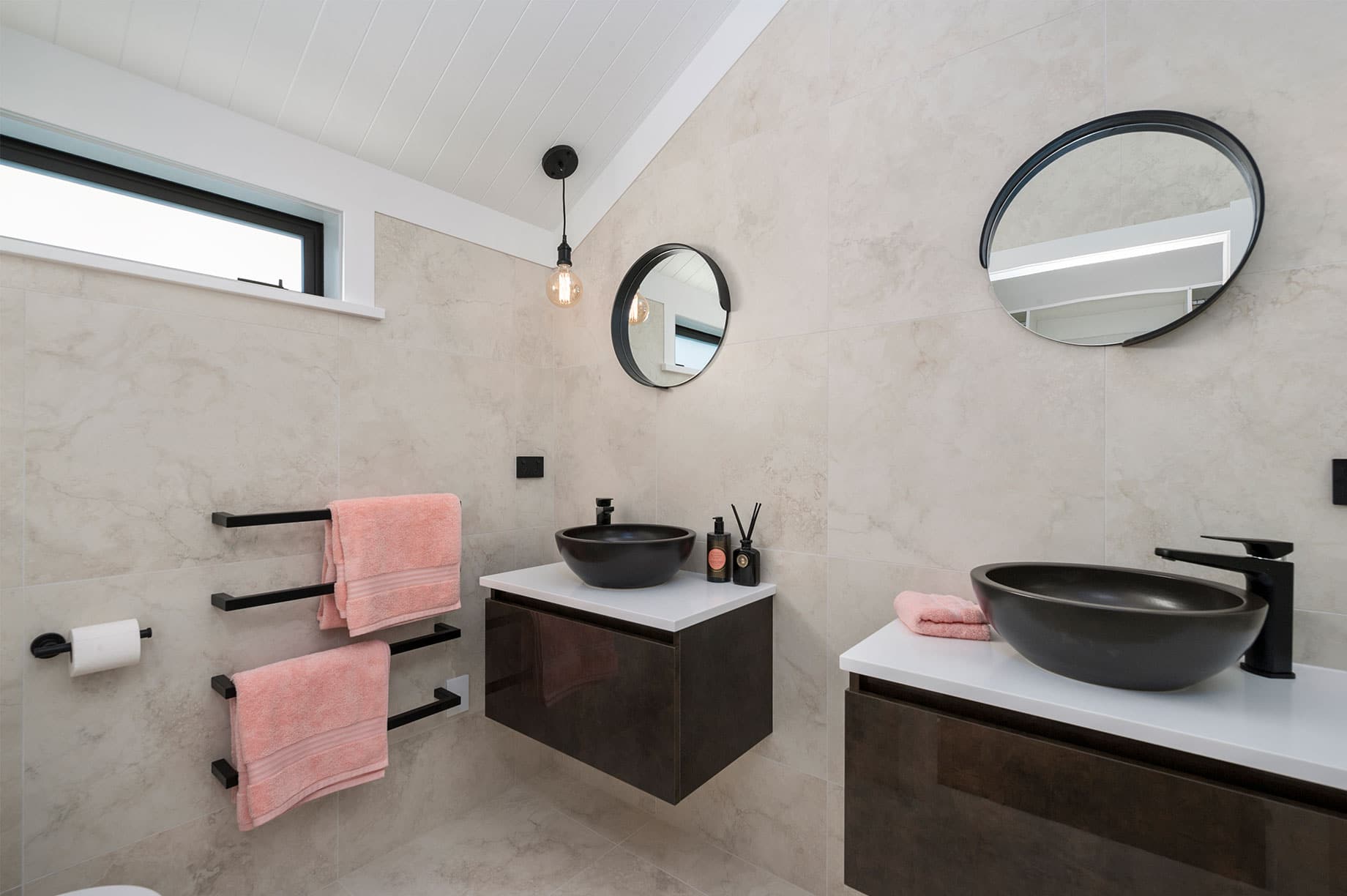 Bathroom with dual black basins and pink towels
