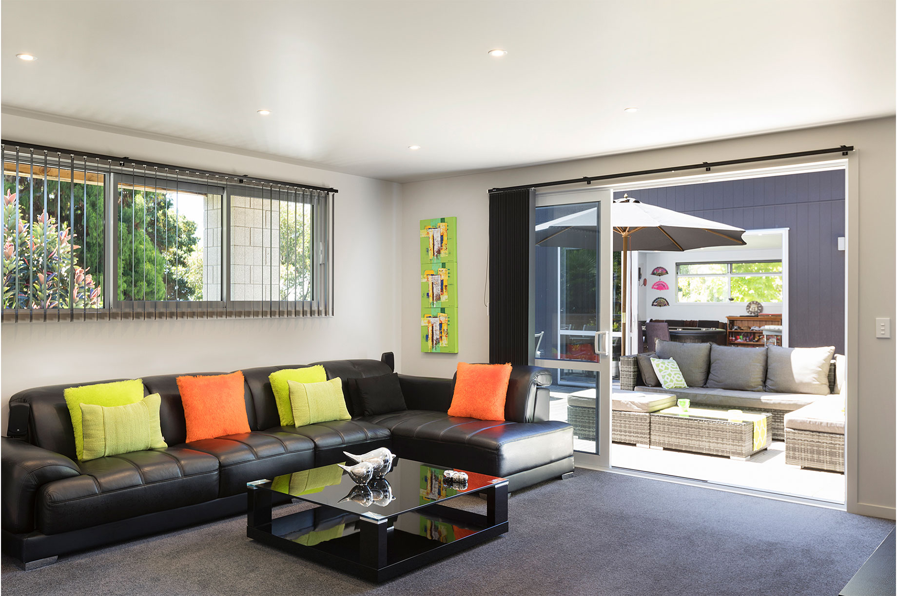 Lounge interior with a black leather couch and colourful pillows